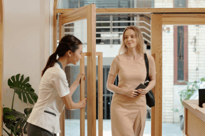 Esthéticienne accueillant une cliente à l’entrée d’un institut de beauté, illustrant la relation de confiance avant la vente en institut de beauté